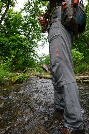 ETHIC Approach Pants in Slate, wet to the shin while wading, showing the reinforced knee panels