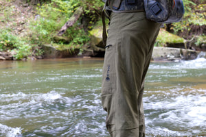 Approach Pants in Freestone, wet from wading, showing the knee panels, zippered cargo pocket, and logo