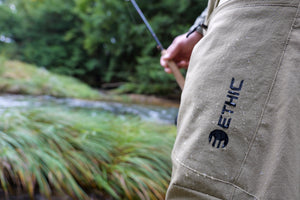Creek water beading on the DWR-treated face of ETHIC Approach Pants in Freestone, logo on the thigh